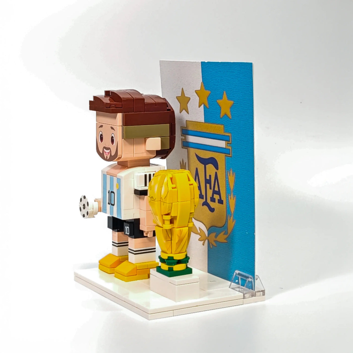 Left side of Popal Messi brick figurine wearing Argentina jersey, standing next to a World Cup trophy — football legend toy